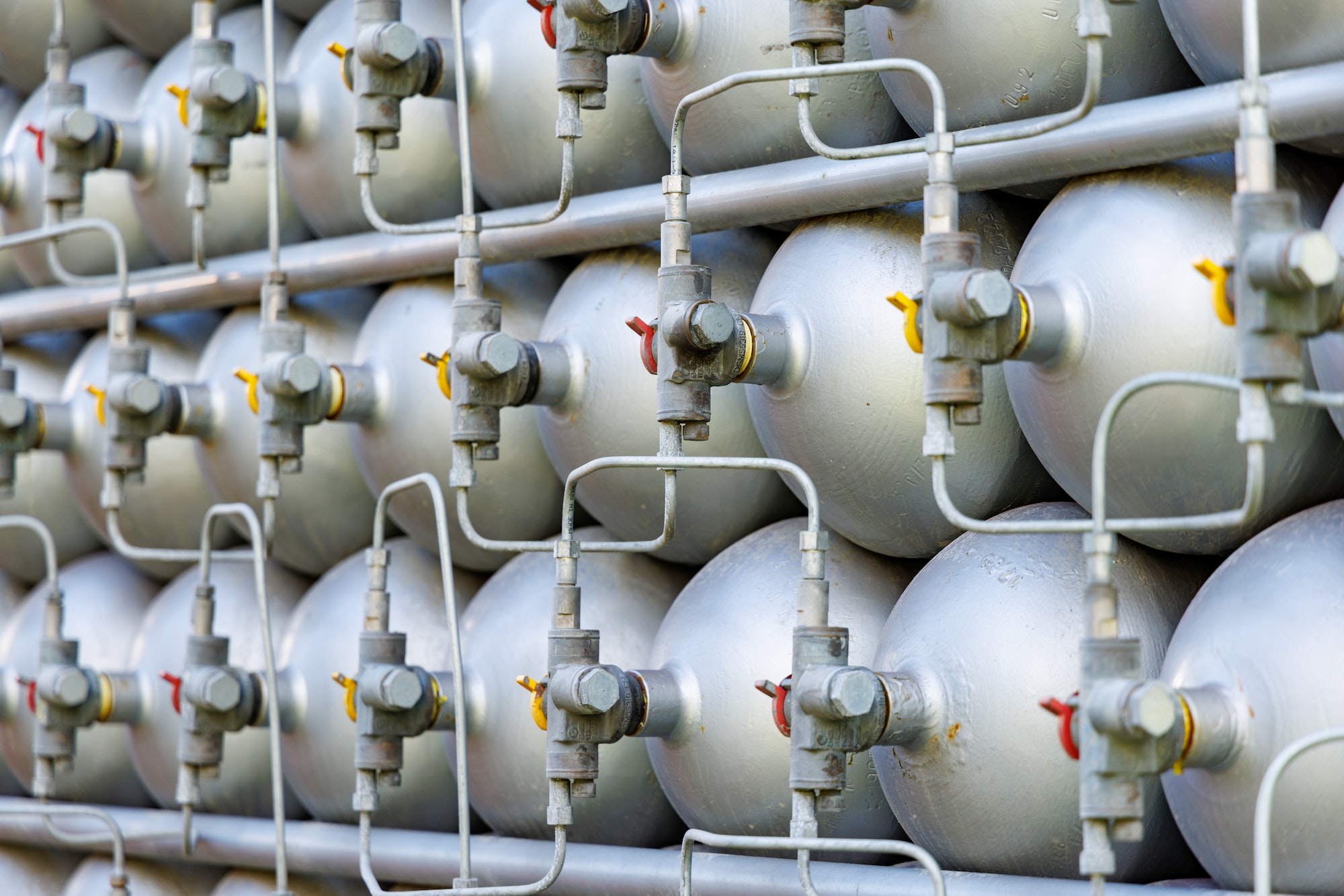 A lot of bottles filled with gas or gasoline are stacked in piles